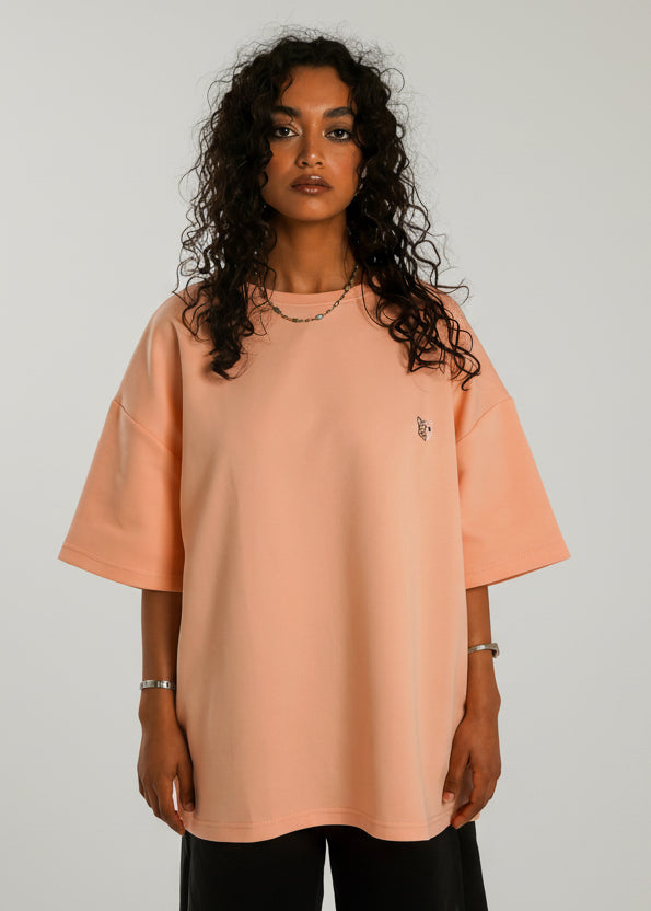 Woman wearing a peach-colored oversized t-shirt on a white background